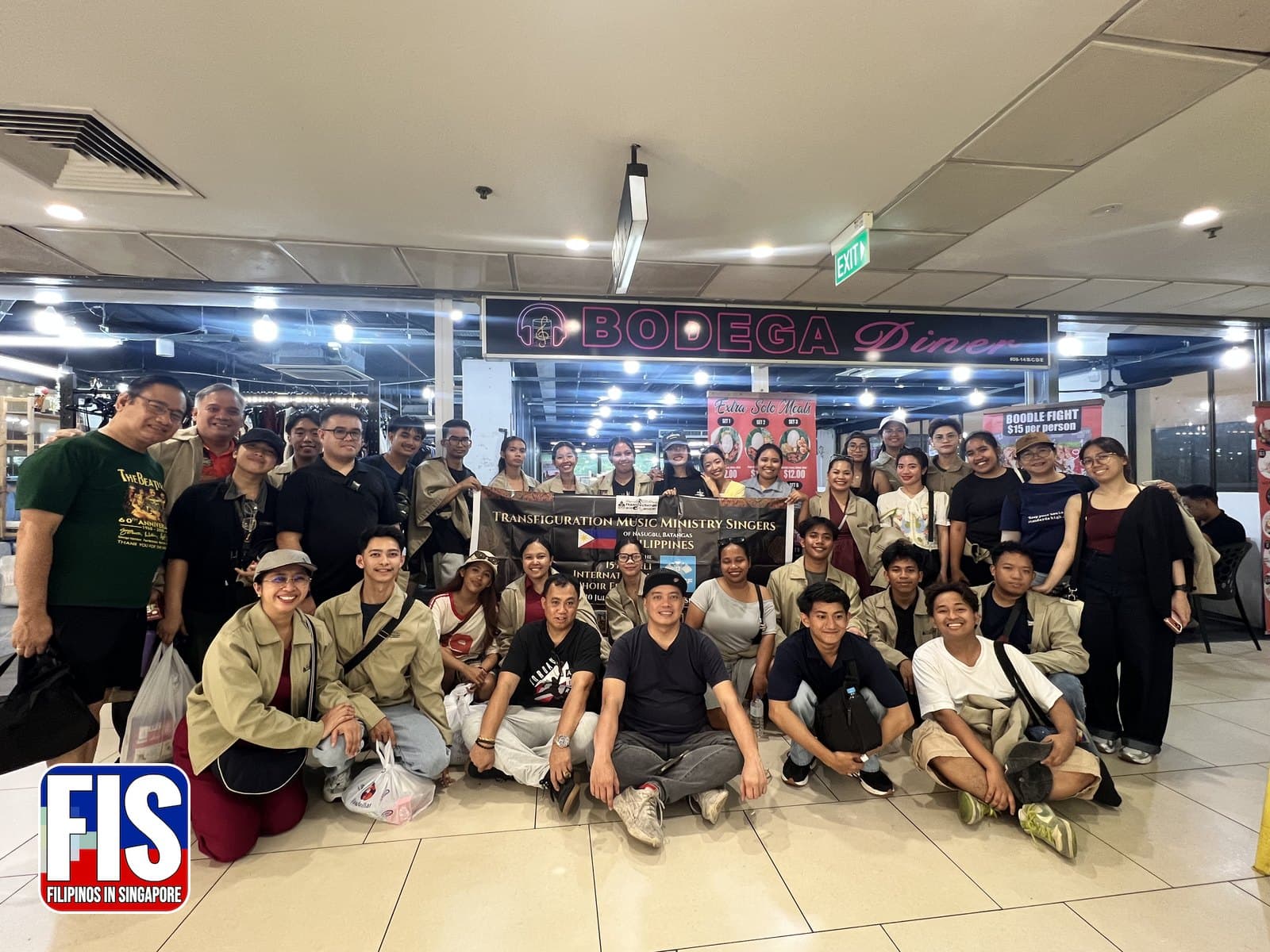 The Transfiguration Music Ministry Singers pose with their banner at Bodega Diner, Lucky Plaza, after the 15th Bali International Choir Festival