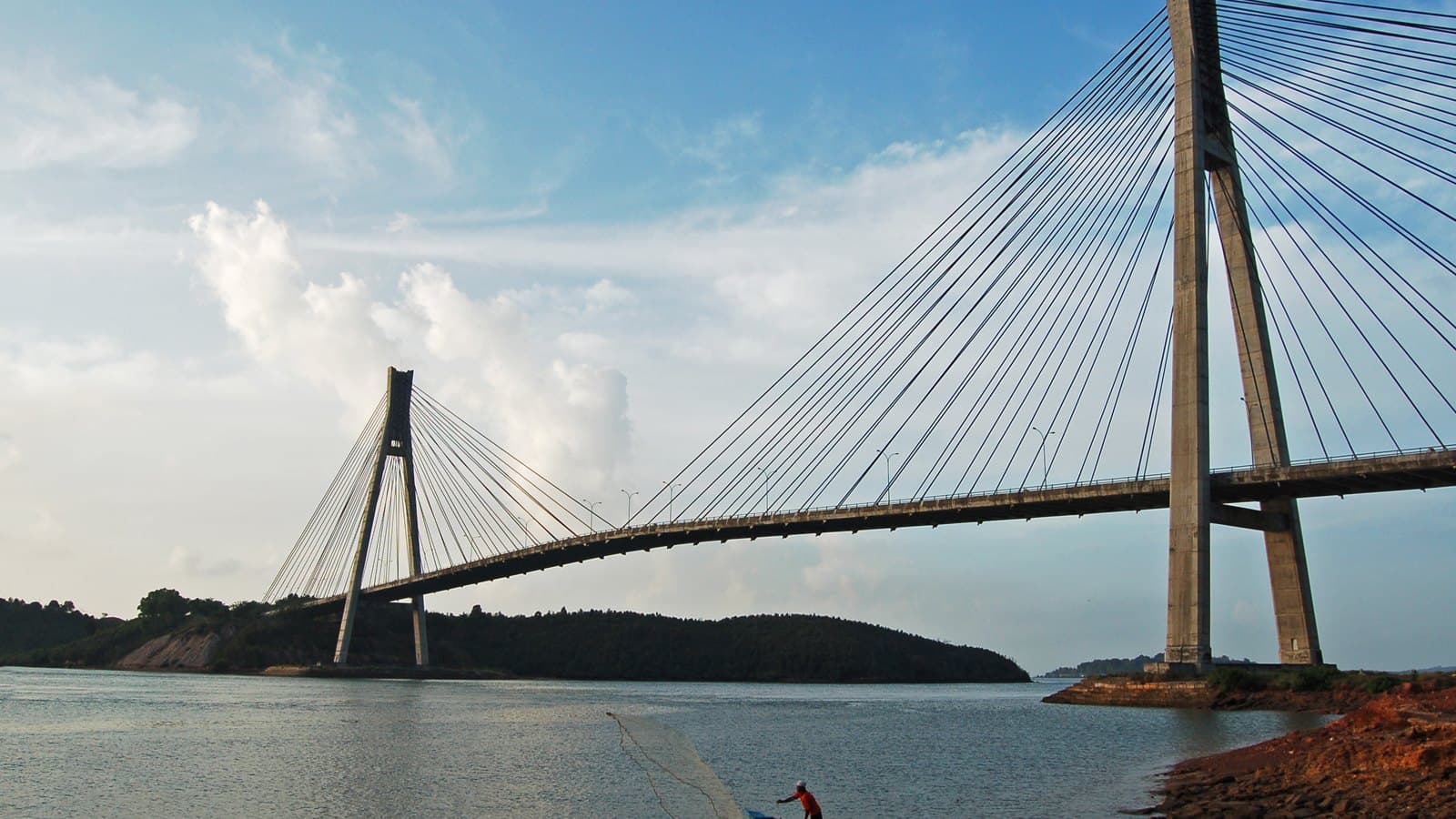 Barelang Bridge in Batam with a fisherman casting a net in the water below