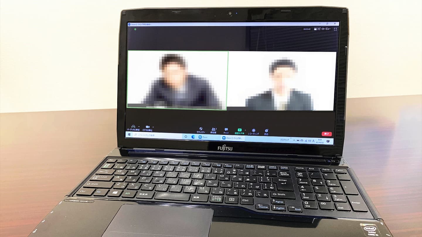 A laptop showing a video call with blurred faces