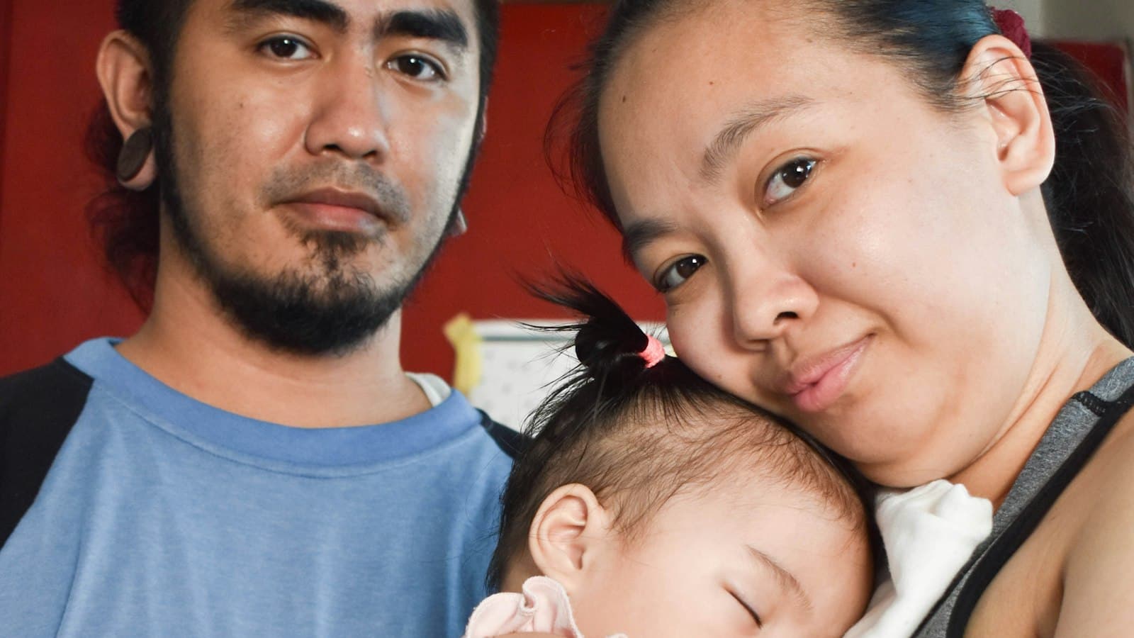 Filipino parents holding their sleeping baby daughter