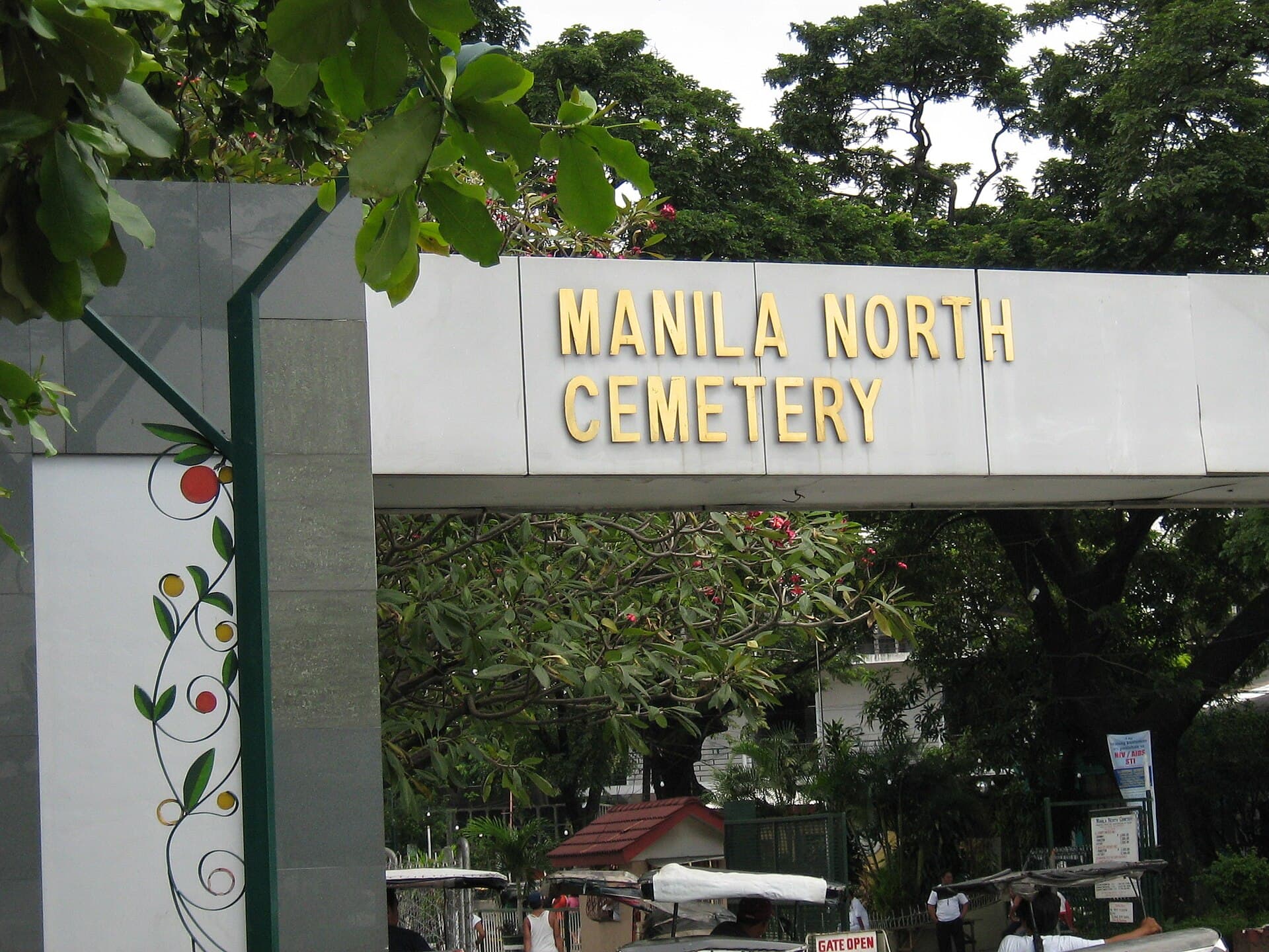 The gold-lettered entrance gate of Manila North Cemetery in the Philippines, framed by trees