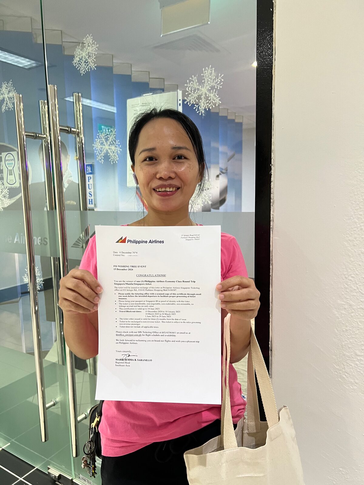 The Wishing Tree winner holding the official Philippine Airlines congratulations certificate confirming her Singapore–Manila roundtrip ticket