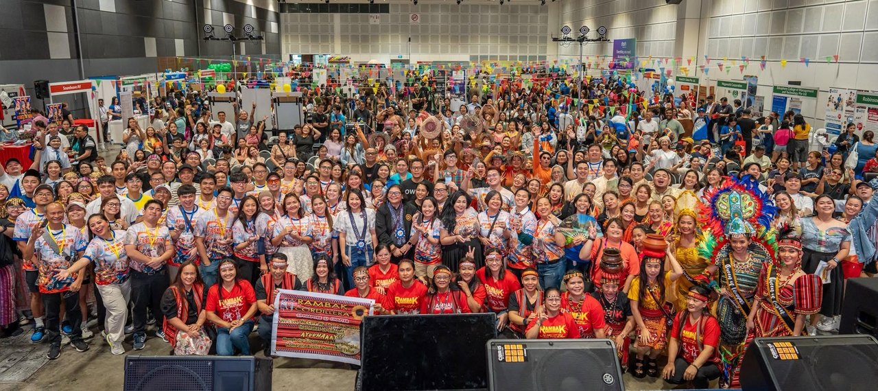 The full Fiestang Pinoy 2026 crowd packed into Suntec Hall 406 in Singapore, hundreds of Filipinos in festival shirts and Cordillera dress gathered for a group photo with cultural performers in front