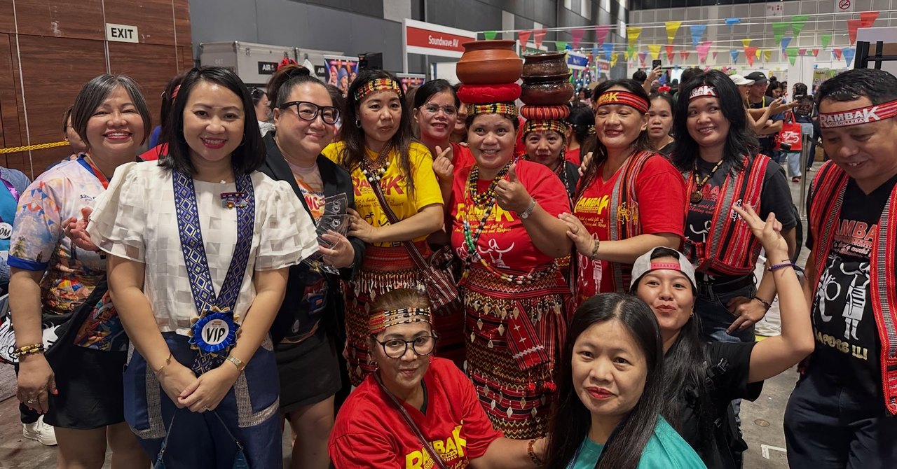 Members of the Rambak Cordillera Singapore contingent in traditional woven dress, some balancing clay pots on their heads, pose with a VIP guest at Fiestang Pinoy 2026