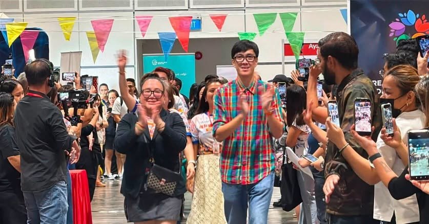Guests walk a runway between rows of kababayan holding up phones to film them at Fiestang Pinoy 2026 in Suntec, Singapore