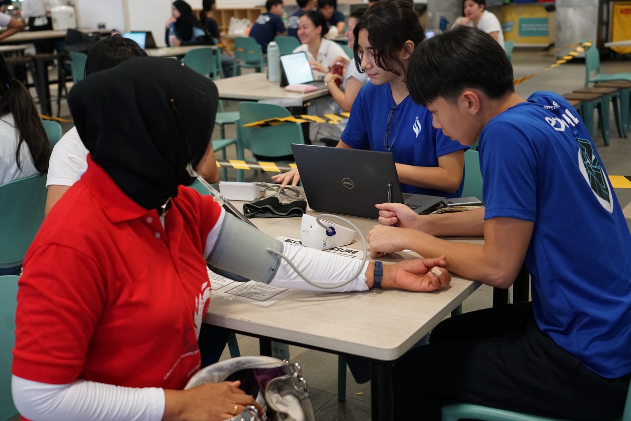 Volunteers taking the blood pressure of a domestic worker at an MHM screening