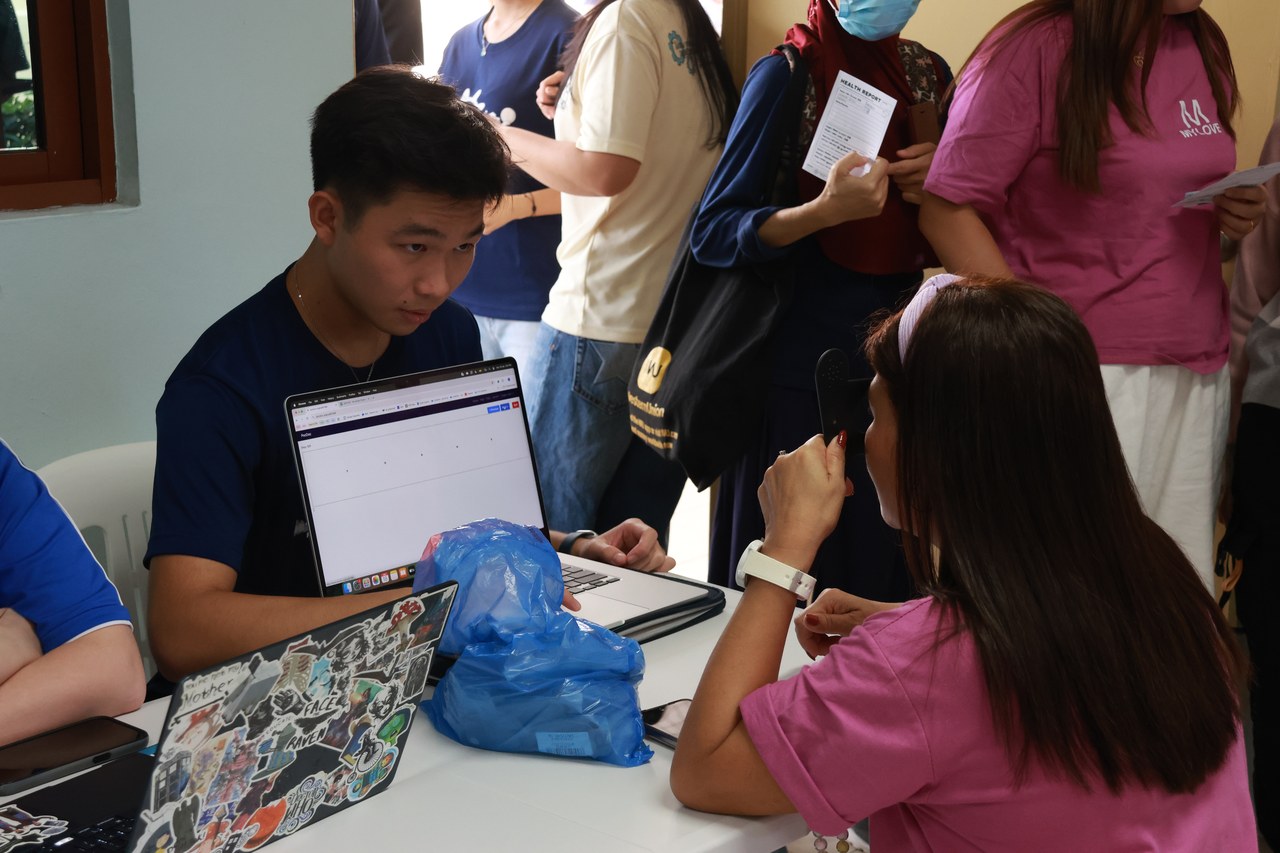 Registration desk at an MHM session — a volunteer assists a worker filling forms