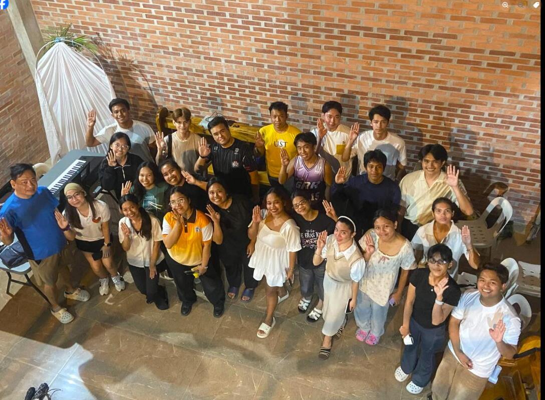 Members of the Transfiguration Music Ministry Singers raise the sign-language letter B at a rehearsal before flying to Bali